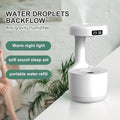 White anti-gravity humidifier with digital clock and water droplets floating, on white table with green plant background