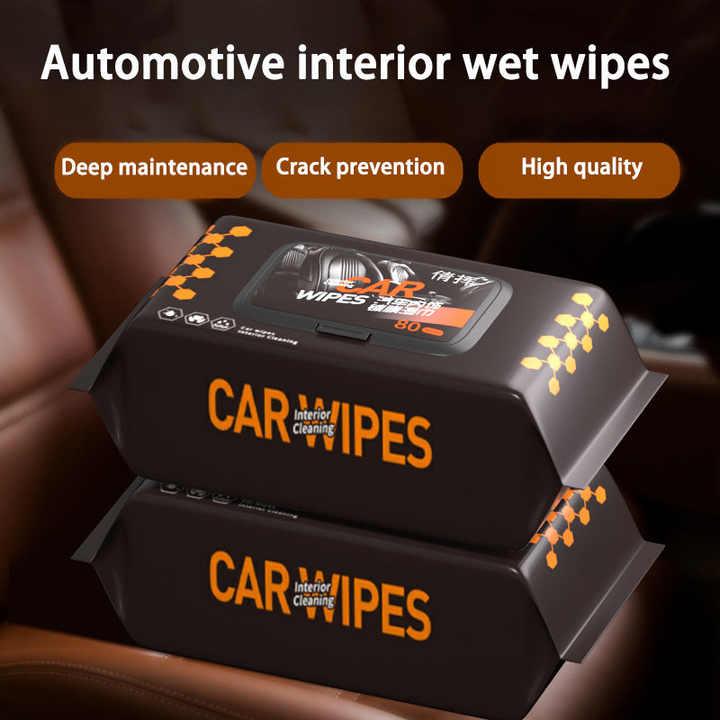 Stacks of black packages labeled Car Interior Cleaning Wipes sitting on a brown leather car seat, highlighting automotive interior wet wipes for deep maintenance and crack prevention