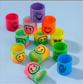 Colorful plastic spring toys with various smiley and playful faces on a light blue background