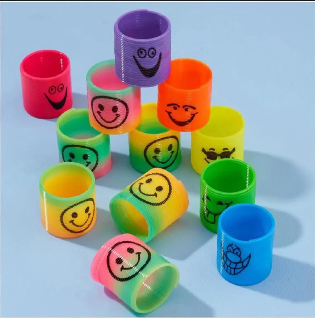 Colorful plastic spring toys with various smiley and playful faces on a light blue background