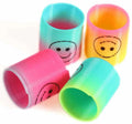 Colorful plastic coil spring toys with smiley face prints in pink, yellow, blue, and green